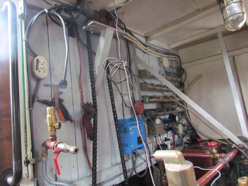De foto toont een interieur met een wirwar van leidingen, kabels, een stopcontact, een blauwe omvormer en een motoronderdeel.