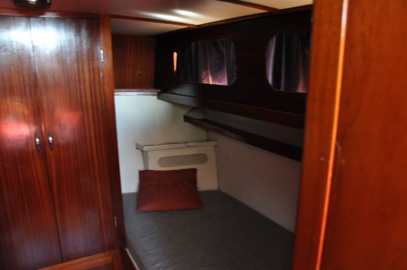 Een kajuit met een bed, een rood kussen, een kast en twee patrijspoorten met gordijnen. — Super Van Craft 1170