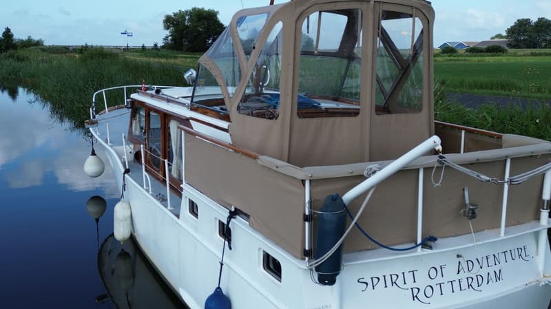Een witte boot met een beige cabrioletkap en de naam "SPIRIT OF ADVENTURE ROTTERDAM" op de spiegel. — Super Van Craft 1170