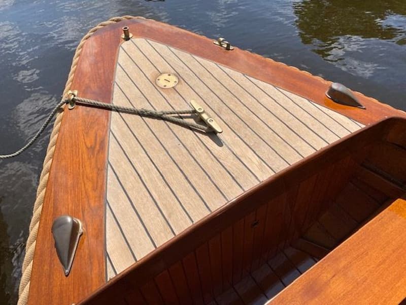 De boeg van een houten boot met een teakhouten dek en een touw dat aan een kikker is vastgemaakt. — De Jongvlet 6.20