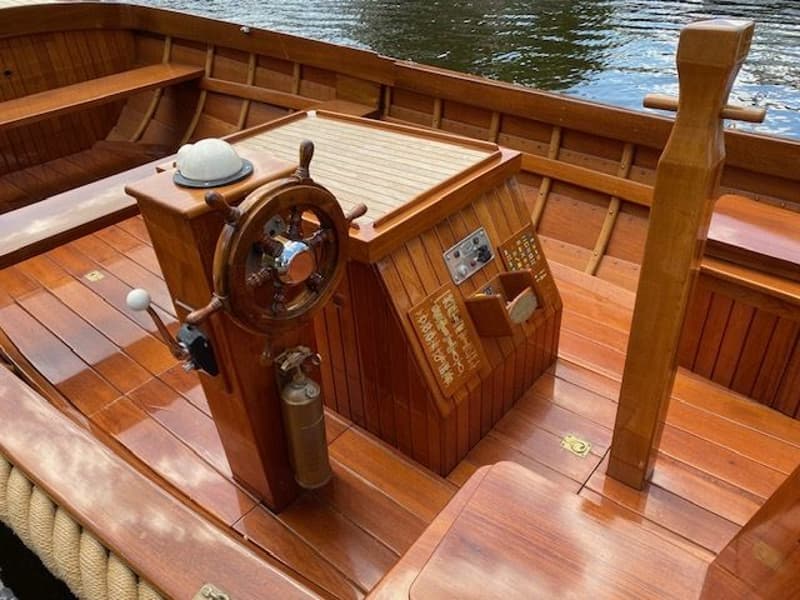 Een houten boot met een stuurwiel, een kompas, een gashendel en een brandblusser in de kuip. — De Jongvlet 6.20