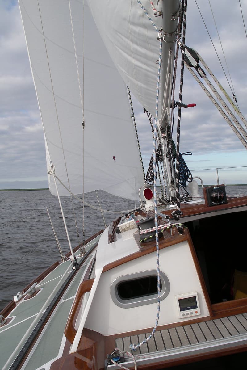 Een zeilboot met een wit zeil, touwen, een kompas en een snelheidsmeter op het dek. — Waarschip 900 +