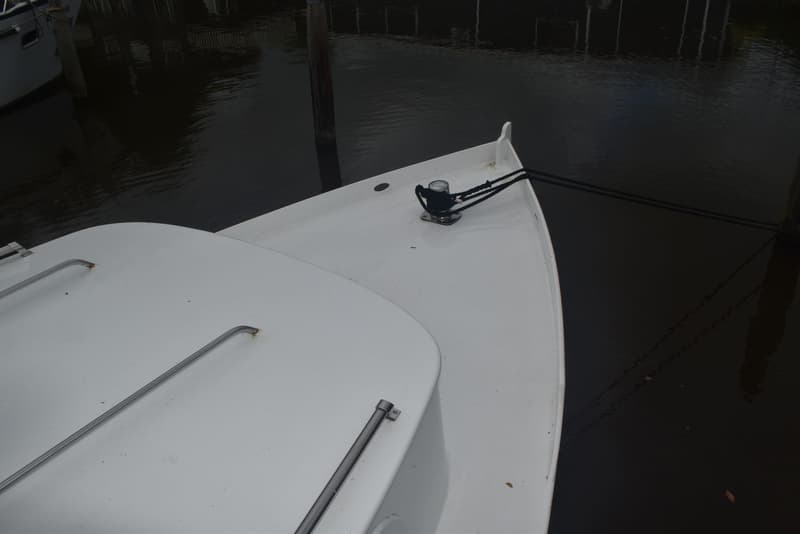 De boeg van een witte boot met een zwarte landvast om een bolder, liggend aan een donker water. — 820C Steilsteven