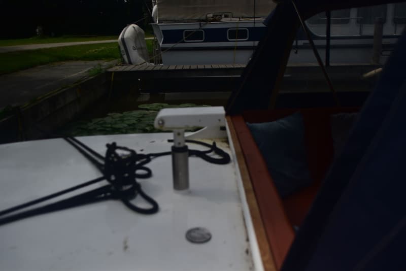 Een boot met een wit dek en een opgerold zwart touw, met op de achtergrond een andere boot en waterlelies. — 820C Steilsteven