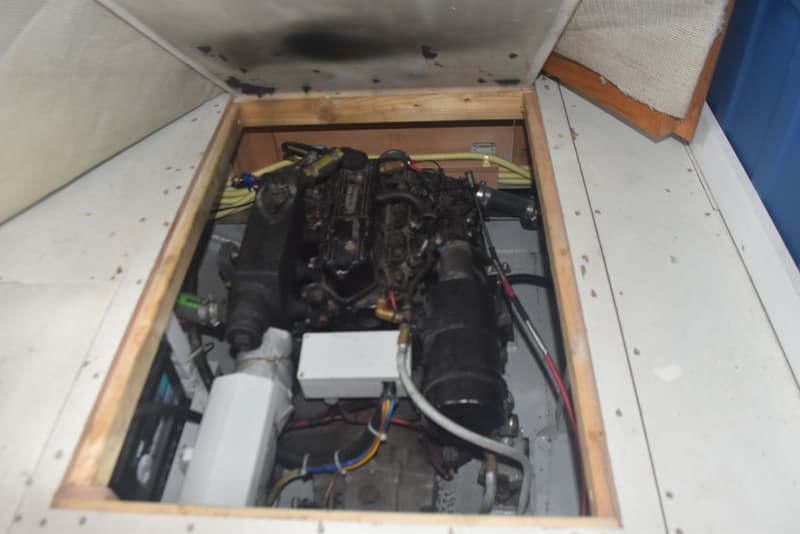 Een open motorruimte met een zwarte motor, omringd door diverse leidingen en kabels.