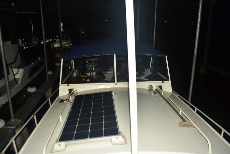 Een boot met een zonnepaneel op het voordek en een blauwe kap over de stuurhut, liggend in een donkere haven. — Doerak 850 AK