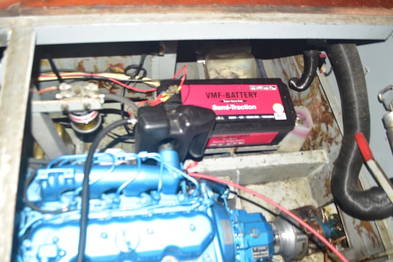 Een blauwe motor met een rode VMF-BATTERY Semi-Traction accu en diverse kabels en slangen.