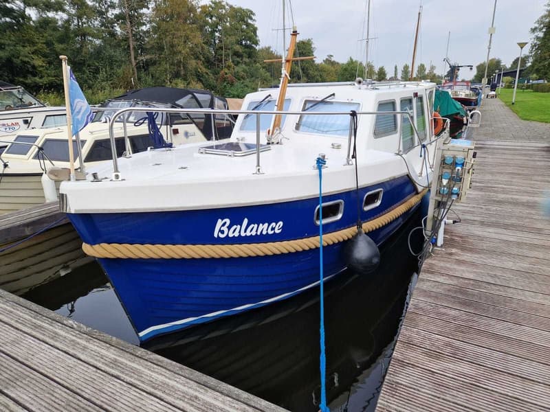 Een blauw-witte boot met de naam "Balance" ligt afgemeerd aan een houten steiger. — Drammer 8.20 Classic