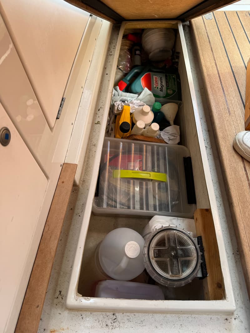 Een open opbergruimte met diverse flessen, een Castrol Magnatec fles, een doorzichtige opbergbox en een rond, doorzichtig…