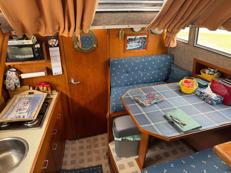 De foto toont het interieur van een boot met een kombuis, zithoek, ramen en gordijnen. — Neptunus 107 TWIN