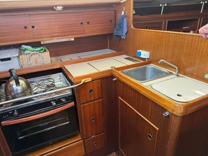 Een kombuis met een fornuis, oven, gootsteen en houten kasten.