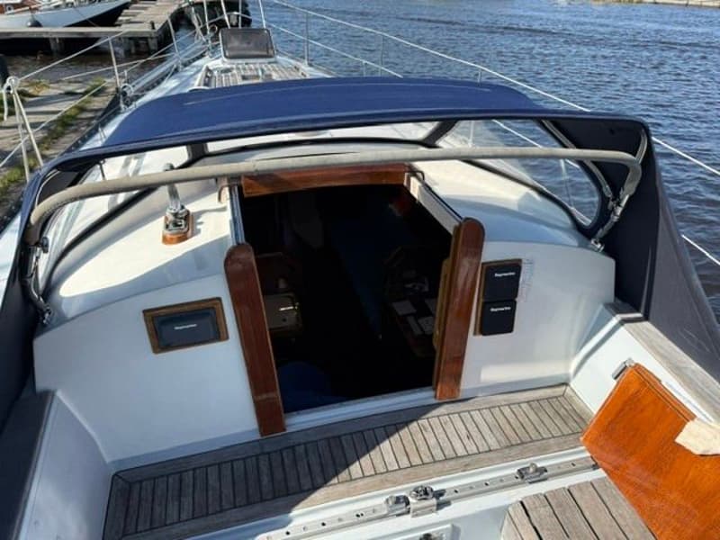 Een bovenaanzicht van de kuip van een zeilboot met een blauwe buiskap en een houten vloer. — Victoire 34 S-spant