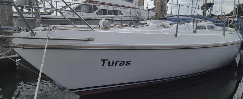 Een witte zeilboot met de naam "Turas" op de romp ligt aangemeerd in het water. — Contest 36 Ketch