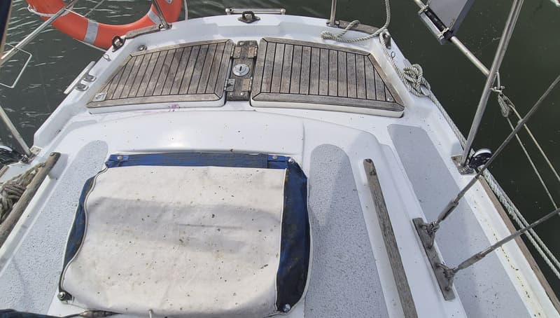 De foto toont het dek van een boot met houten luiken, een reddingsboei, touwen en een wit-blauw zeilhoes. — Contest 36 Ketch