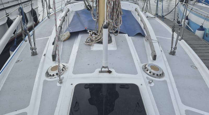 Een bovenaanzicht van het dek van een zeilboot met een mast, touwen, luiken en een blauw zeil. — Contest 36 Ketch