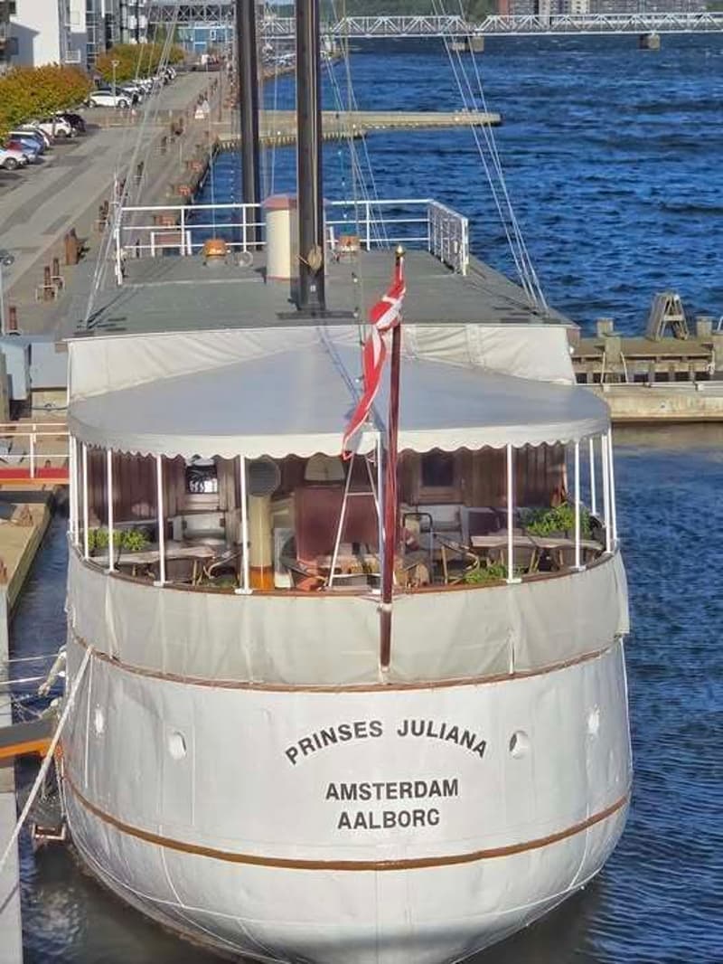 De witte boot toont haar spiegel met de naam "PRINSES JULIANA" en de thuishavens "AMSTERDAM AALBORG". — Horeca Schip 37.40
