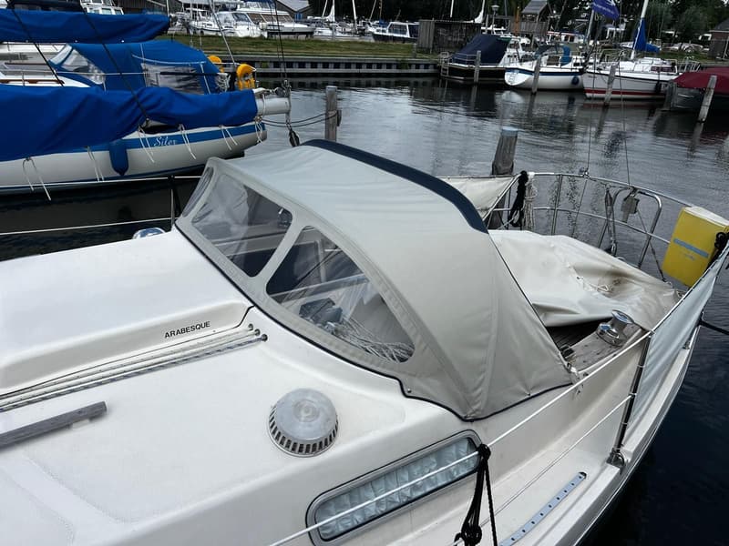 Een witte zeilboot met een lichtgrijze buiskap en de naam "ARABESQUE" op het dek ligt in een haven. — Arabesque 30