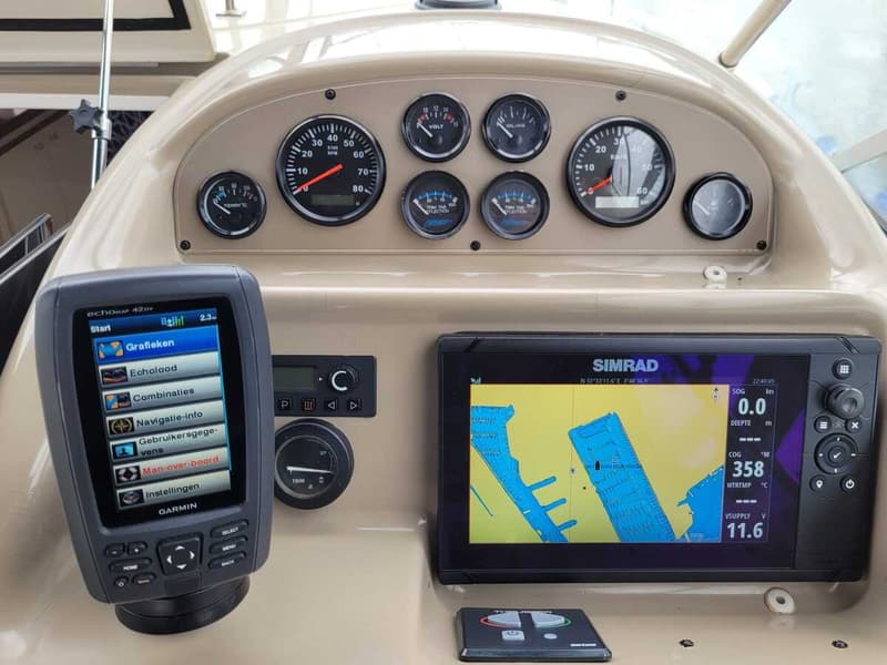 Een dashboard met diverse meters, een Garmin echomap en een Simrad navigatiesysteem.