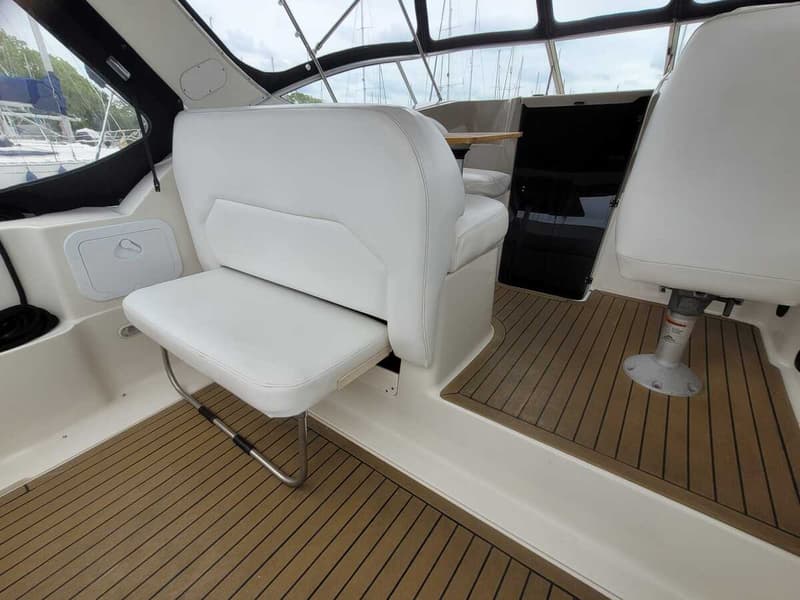 De foto toont een deel van een bootinterieur met witte zitplaatsen en een houten vloer.