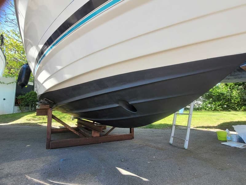 Een witte boot met zwarte onderkant staat op een houten bok op een geasfalteerde ondergrond. — Bayliner 2855 Ciera Sunbridge