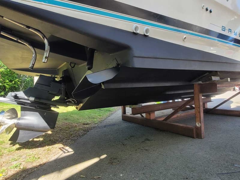 De onderkant van een boot met een buitenboordmotor en schroef, staand op een bruine metalen bok.