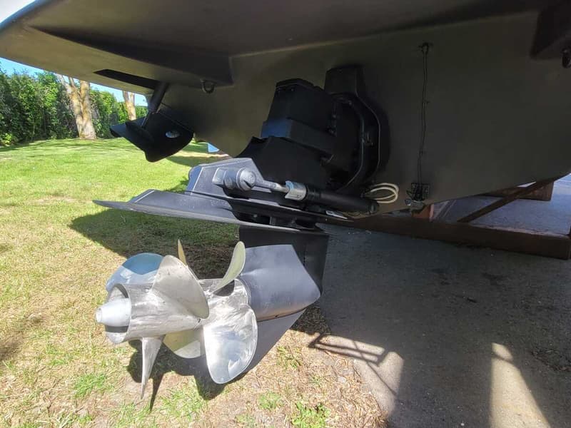 De foto toont de onderkant van een boot met een buitenboordmotor en een zilveren driebladige schroef.