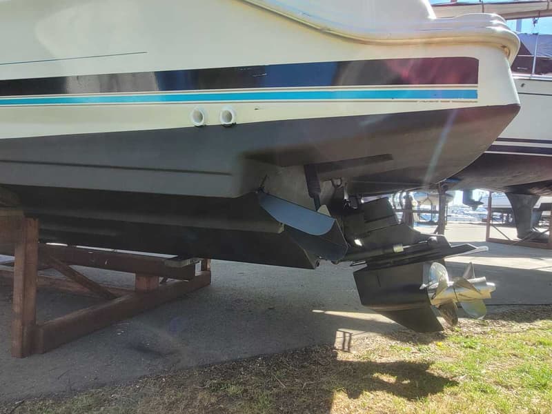 De achterkant van een boot met een buitenboordmotor en schroef, staand op een houten bok op de wal.