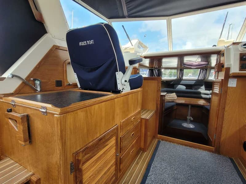 Een interieur van een boot met een blauwe stoel met "ASPER BOAT" erop, een wasbak en houten kasten. — Agder 840 OK