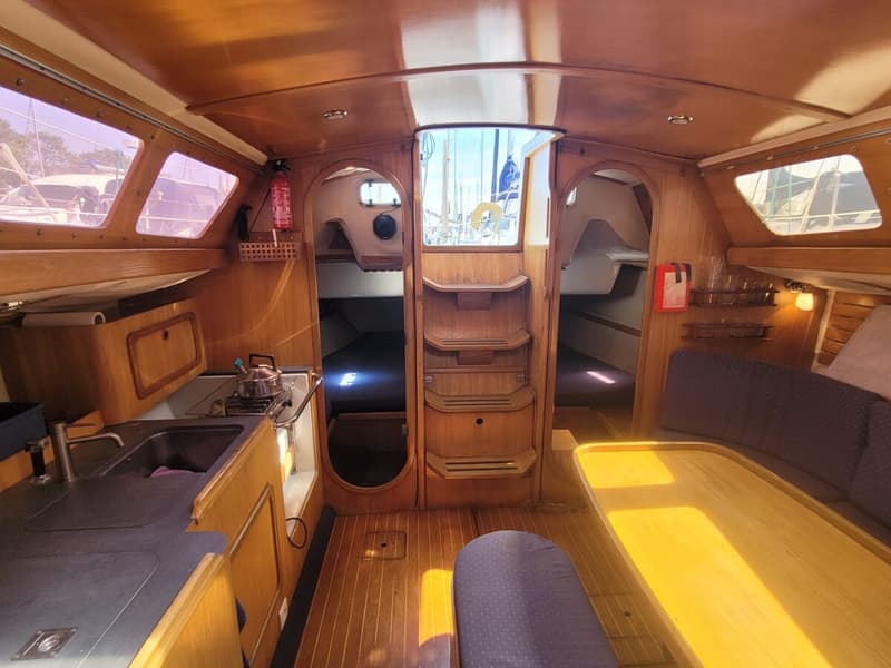 De foto toont het interieur van een boot met een kombuis, zithoek en twee slaapcabines. — Feeling 346