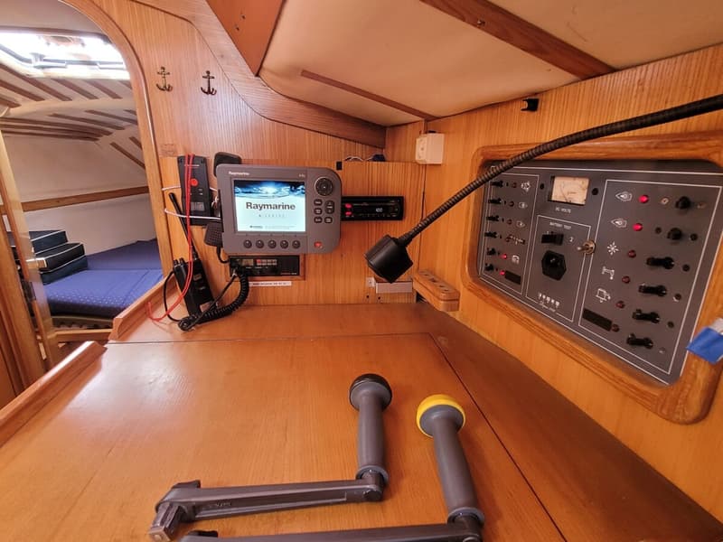 Een houten interieur van een boot met een Raymarine A Series display, een bedieningspaneel en twee lierenhendels.