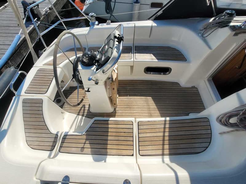 Een bovenaanzicht van de kuip van een zeilboot met een stuurwiel, kompas en teakhouten vloer. — Bavaria 34-2
