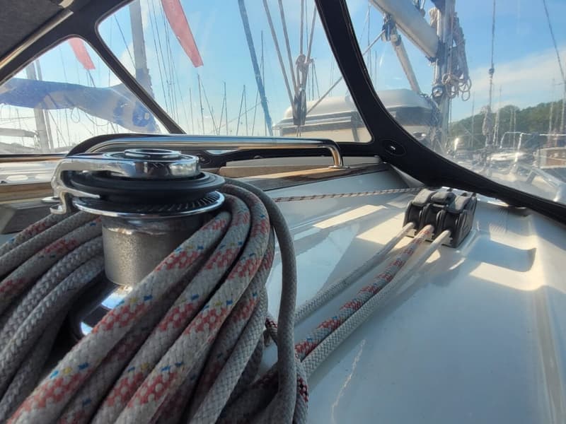 Een detailfoto van een lier met opgerold touw en drie touwklemmen op het dek van een zeilboot. — Bavaria 34-2