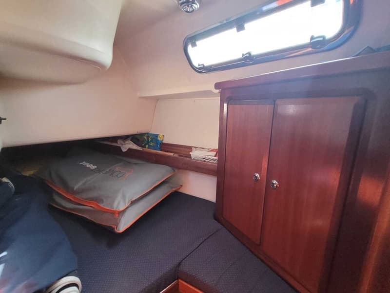 De foto toont een interieur van een boot met een houten kast, een raam en een bed met kussens. — Bavaria 34-2