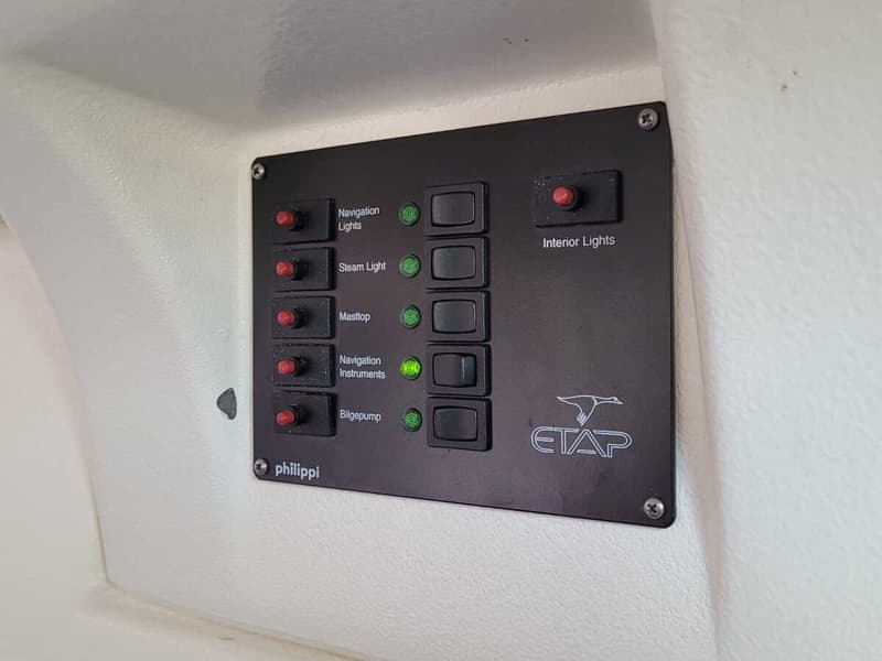 Een zwart bedieningspaneel met rode schakelaars, groene indicatielampjes en labels zoals "Navigation Lights" en "Bilgepump".