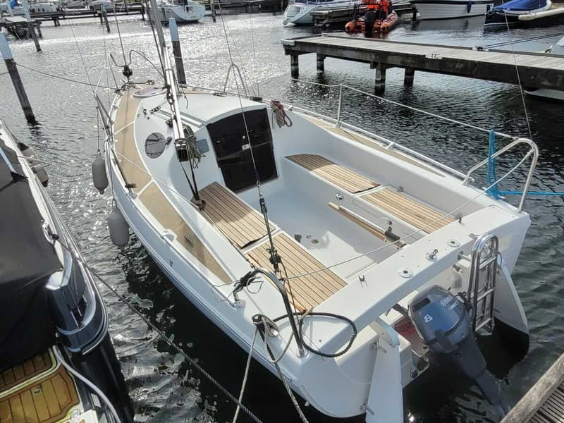 Een witte zeilboot met houten dek en een Yamaha buitenboordmotor ligt afgemeerd in een haven. — Etap 21i