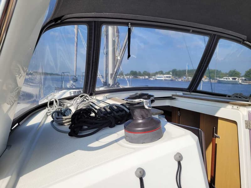 Een lier en touwen op het dek van een zeilboot, met uitzicht op water en andere boten. — Beneteau Oceanis 35