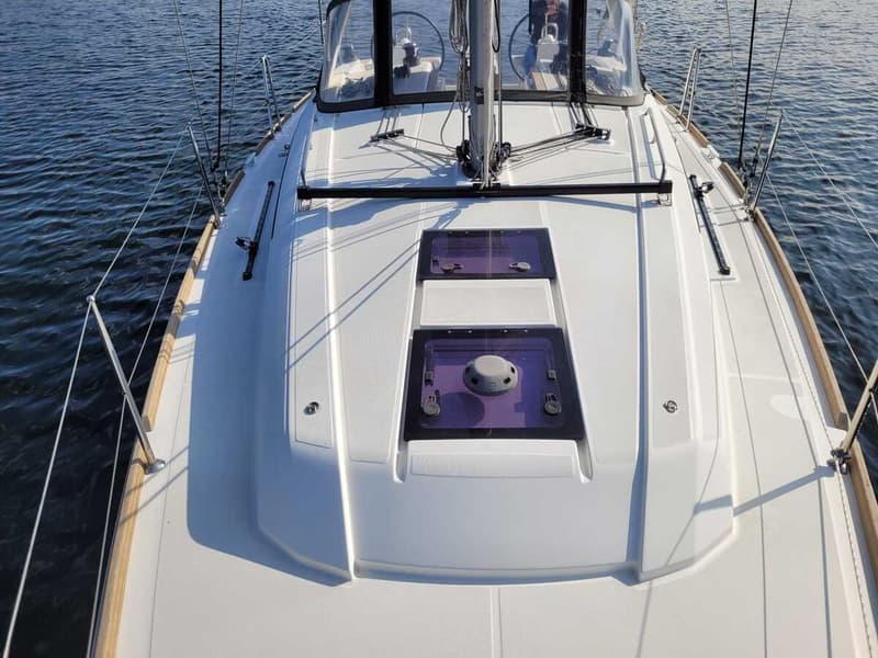Een bovenaanzicht van het voordek van een witte zeilboot met twee luiken en een mast. — Beneteau Oceanis 35