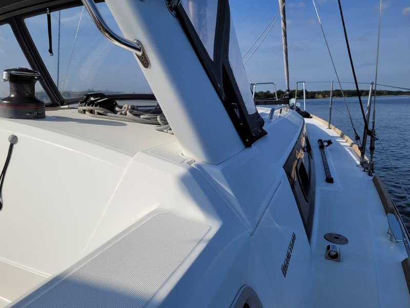 Een witte zeilboot met de tekst "BENETEAU" op de romp, liggend op het water onder een blauwe lucht. — Beneteau Oceanis 35