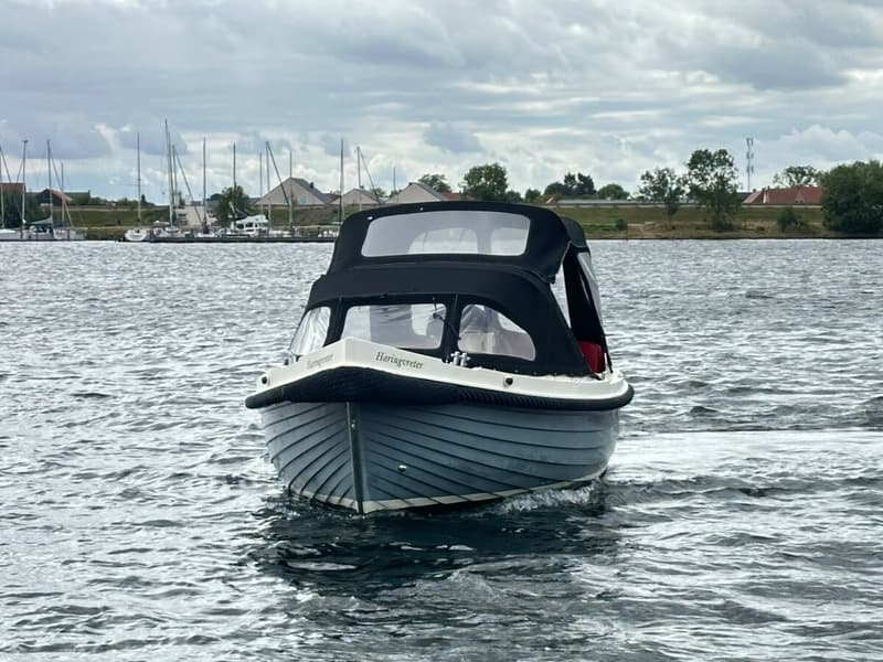 Een blauwe sloep met een zwarte buiskap vaart op het water, met de naam "Haringvreter" op de boeg. — Interboar 22