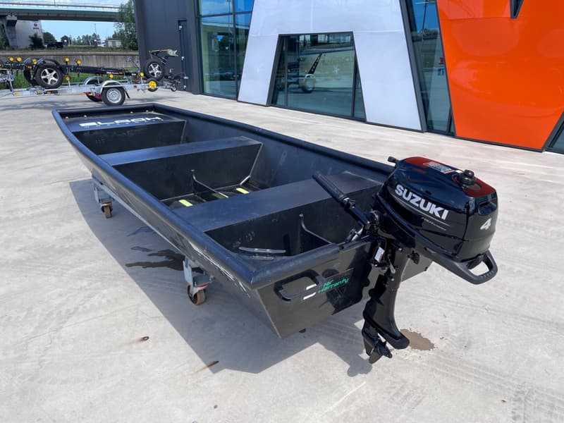 Een zwarte open boot met een Suzuki buitenboordmotor staat op een betonnen ondergrond voor — Black work boats Black Jon 400