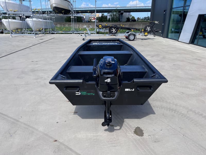 Een zwarte boot met een buitenboordmotor staat op een betonnen ondergrond, met andere boten — Black work boats Black Jon 400