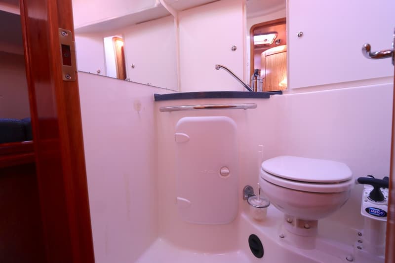 Een badkamer op een boot met een toilet, wastafel en spiegel. — Bavaria 37-3 Cruiser