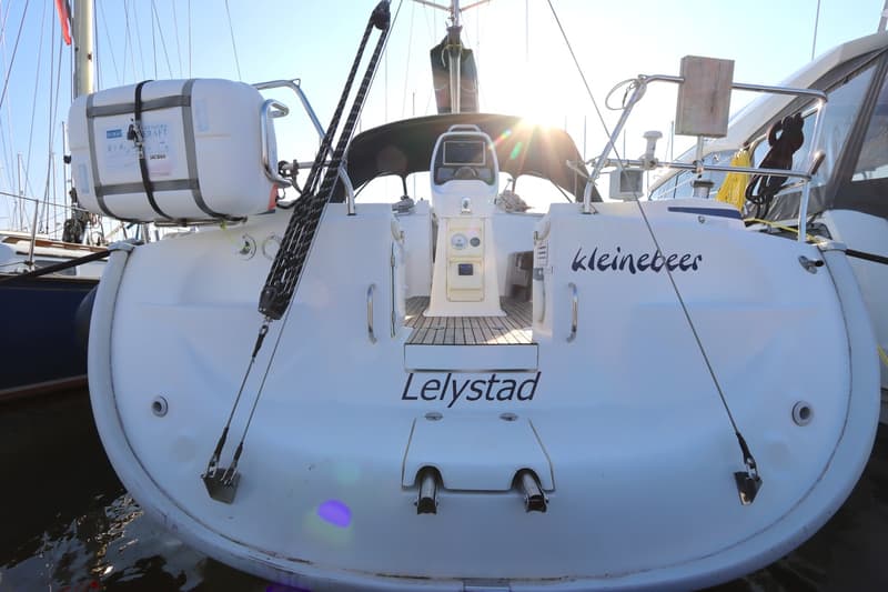 De achterkant van een witte zeilboot met de naam "kleinebeer" en de thuishaven "Lelystad" is zichtbaar.