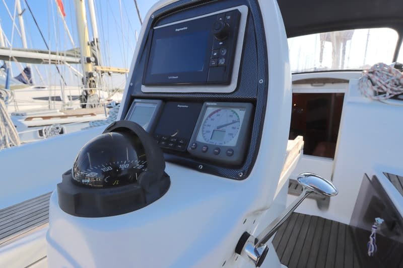Een kompas, Raymarine-schermen en een windmeter zijn zichtbaar op het stuurstandpaneel van een zeilboot.