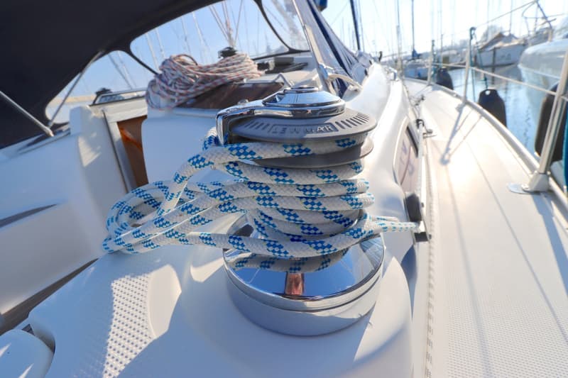 Een lier met wit en blauw touw op het dek van een zeilboot, met andere boten op de achtergrond. — Bavaria 37-3 Cruiser