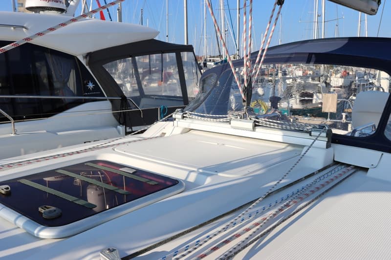 Twee boten liggen naast elkaar in een jachthaven, met touwen en zeilen zichtbaar.