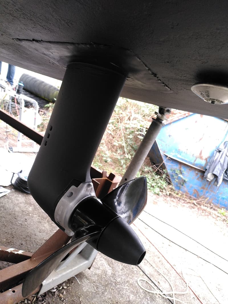 Een zwart geverfde saildrive met een driebladige schroef is gemonteerd onder een donkere romp.