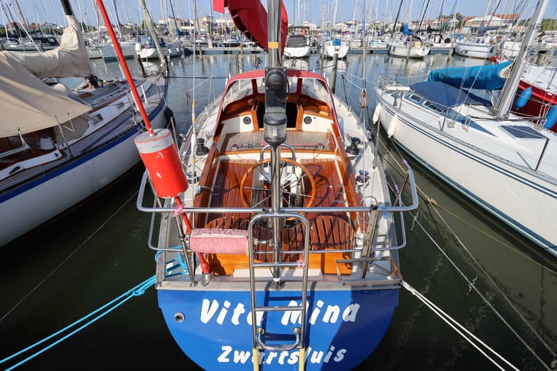 Een blauwe zeilboot met de naam "Vitamina Zwartsluis" ligt in een jachthaven tussen andere boten. — Koopmans 36