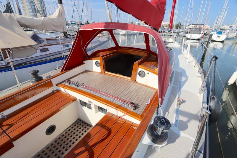 De foto toont de kuip van een zeilboot met houten banken, een rode buiskap en een houten dek. — Koopmans 36