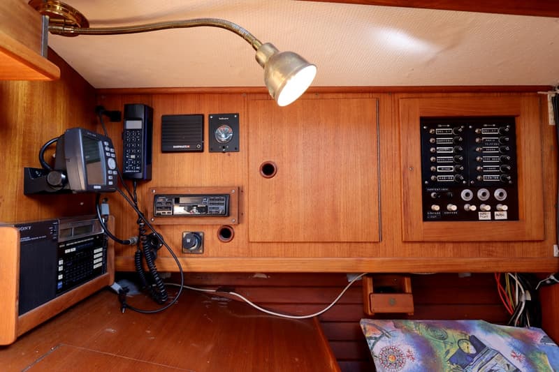 Een houten interieur met een lamp, diverse elektronica en een schakelpaneel.